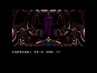 A screenshot from the 1989 video game "Zero Wing." The screen depicts the bridge of a spaceship with a hologram of a man in a purple robe and the words "CAPTAIN: IT'S YOU ! !" 